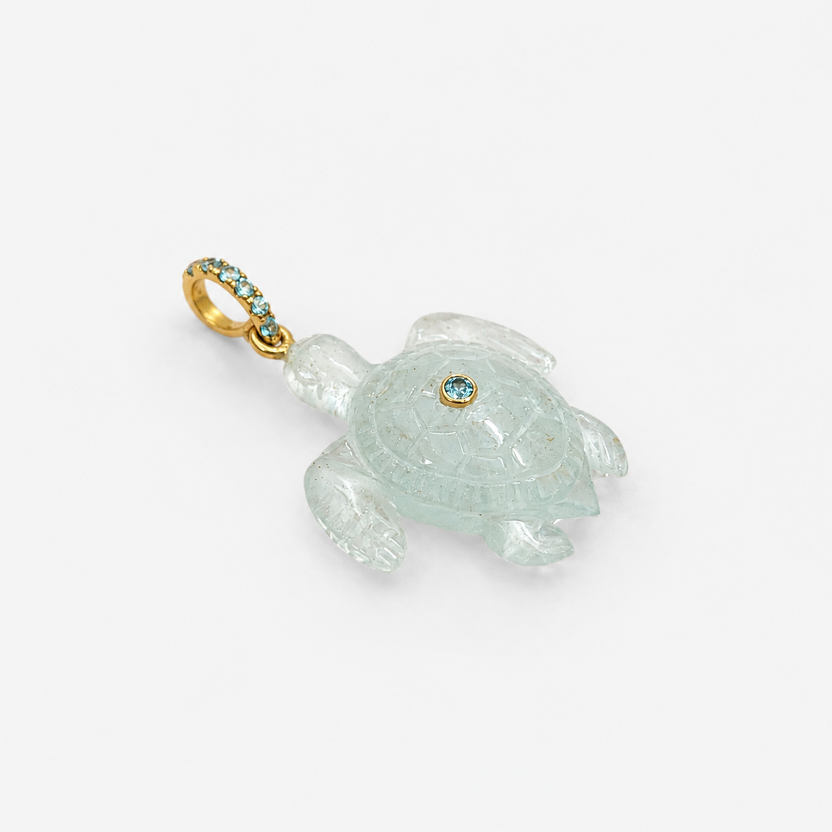 Hand-carved aquamarine sea turtle pendant at diagonal angle with bail at top left, 14k yellow gold pavé ring bail set with Swiss blue topaz accents and bezel-set Swiss blue topaz on shell, translucent pale blue gemstone with engraved shell pattern and extended flippers