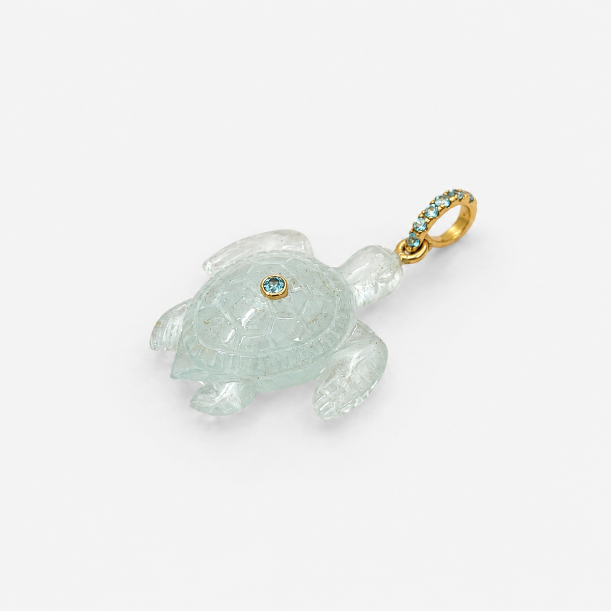 Hand-carved aquamarine sea turtle pendant at diagonal angle showing full shell, with 14k yellow gold pavé ring bail set with Swiss blue topaz accents and bezel-set Swiss blue topaz on shell, translucent pale seafoam blue gemstone with detailed carapace engraving