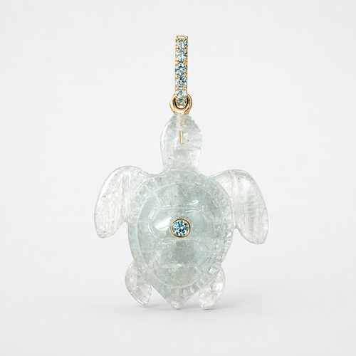 Front-facing hand-carved aquamarine sea turtle pendant with 14k yellow gold pavé bail set with Swiss blue topaz accents and bezel-set Swiss blue topaz centered on shell, translucent icy blue gemstone with symmetrical flipper spread and engraved carapace detail