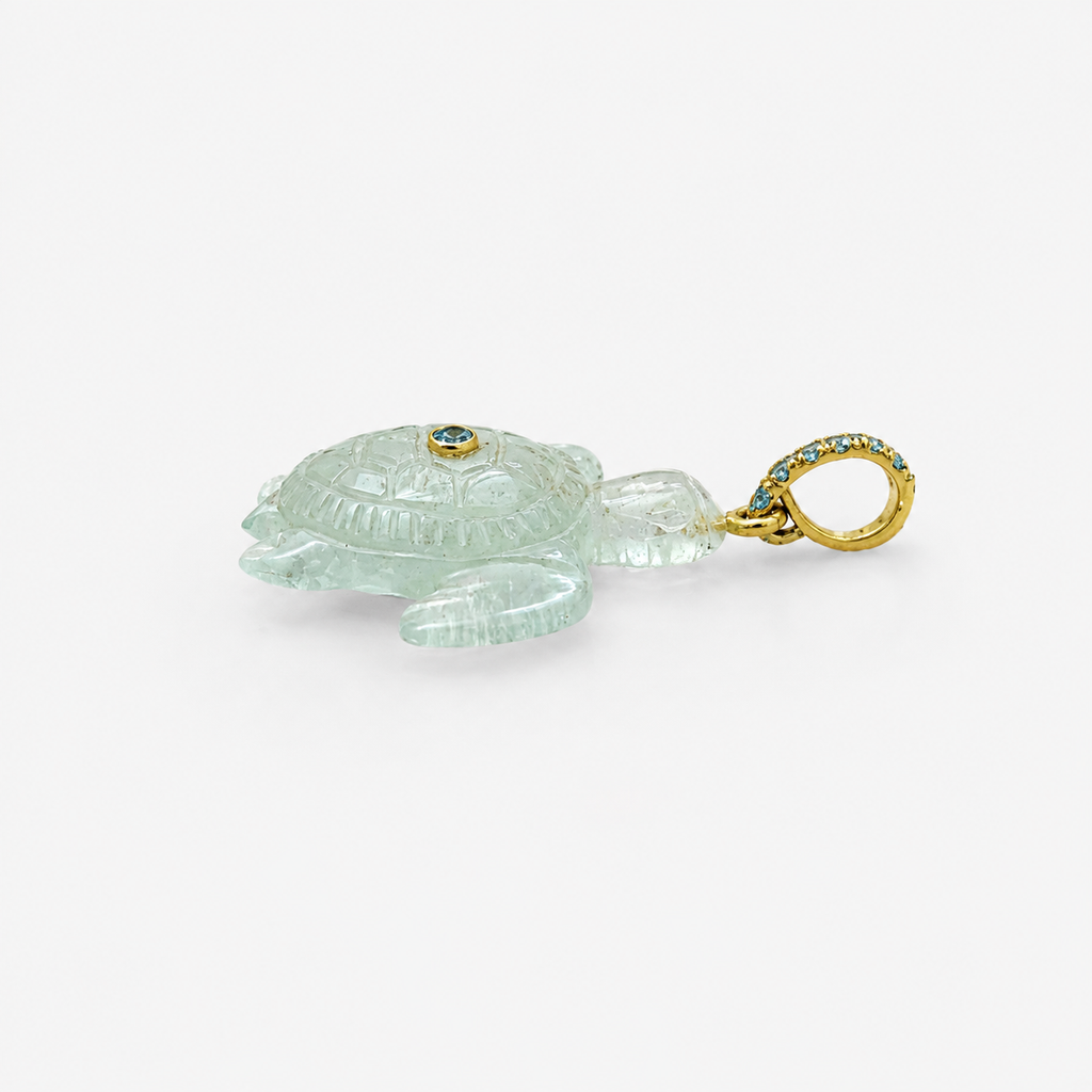 Hand-carved aquamarine sea turtle pendant in side profile view, with 14k yellow gold pavé ring bail set with Swiss blue topaz accents and bezel-set Swiss blue topaz on shell, translucent pale blue gemstone with engraved shell and flipper detail