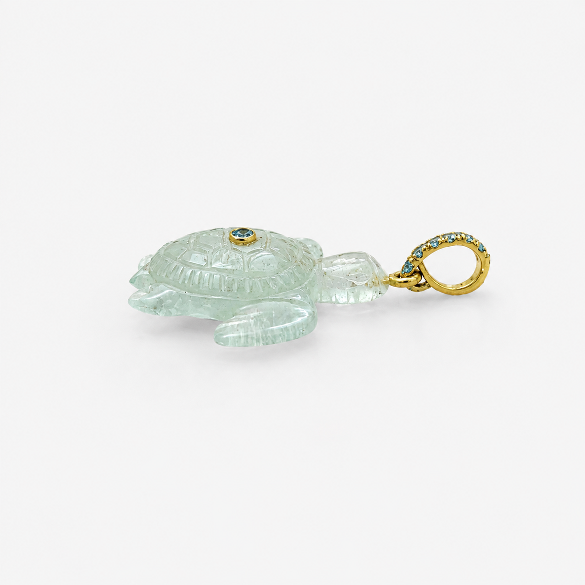 Hand-carved aquamarine sea turtle pendant in side profile view, with 14k yellow gold pavé ring bail set with Swiss blue topaz accents and bezel-set Swiss blue topaz on shell, translucent pale blue gemstone with engraved shell and flipper detail