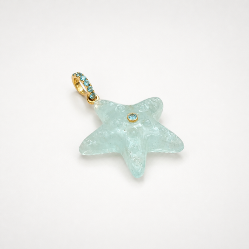 Hand-carved aquamarine starfish pendant at diagonal angle with bail at top left, 14k yellow gold pavé bail set with Swiss blue topaz accents and bezel-set Swiss blue topaz center accent, translucent pale seafoam blue gemstone with engraved bubble and swirl texture