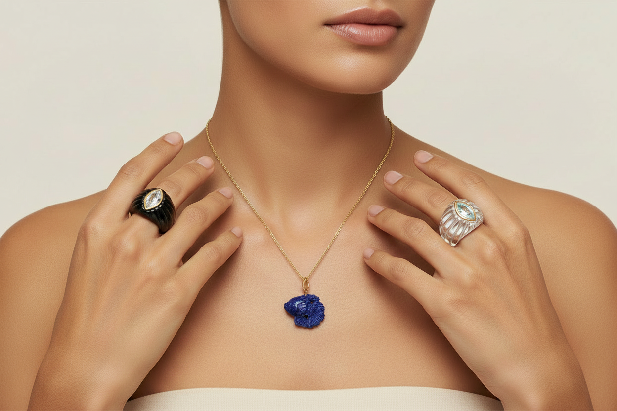 Model wearing lapis lazuli carved fish pendant on gold chain with black onyx white topaz marquise ring and rock crystal sky blue topaz marquise stone ring
